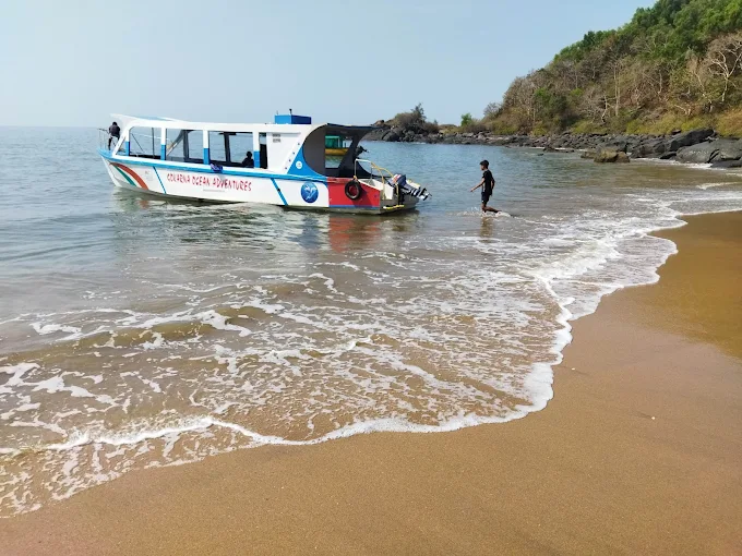 The boat anchored in the shallows of a quiet sandy beach