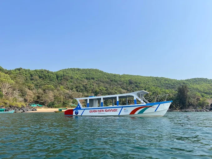 The boat cruising past green hills and a sandy cove